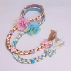 Prinsesseparyk med lange fletninger og hårbånd, med blå blomster og hvide fletninger.
